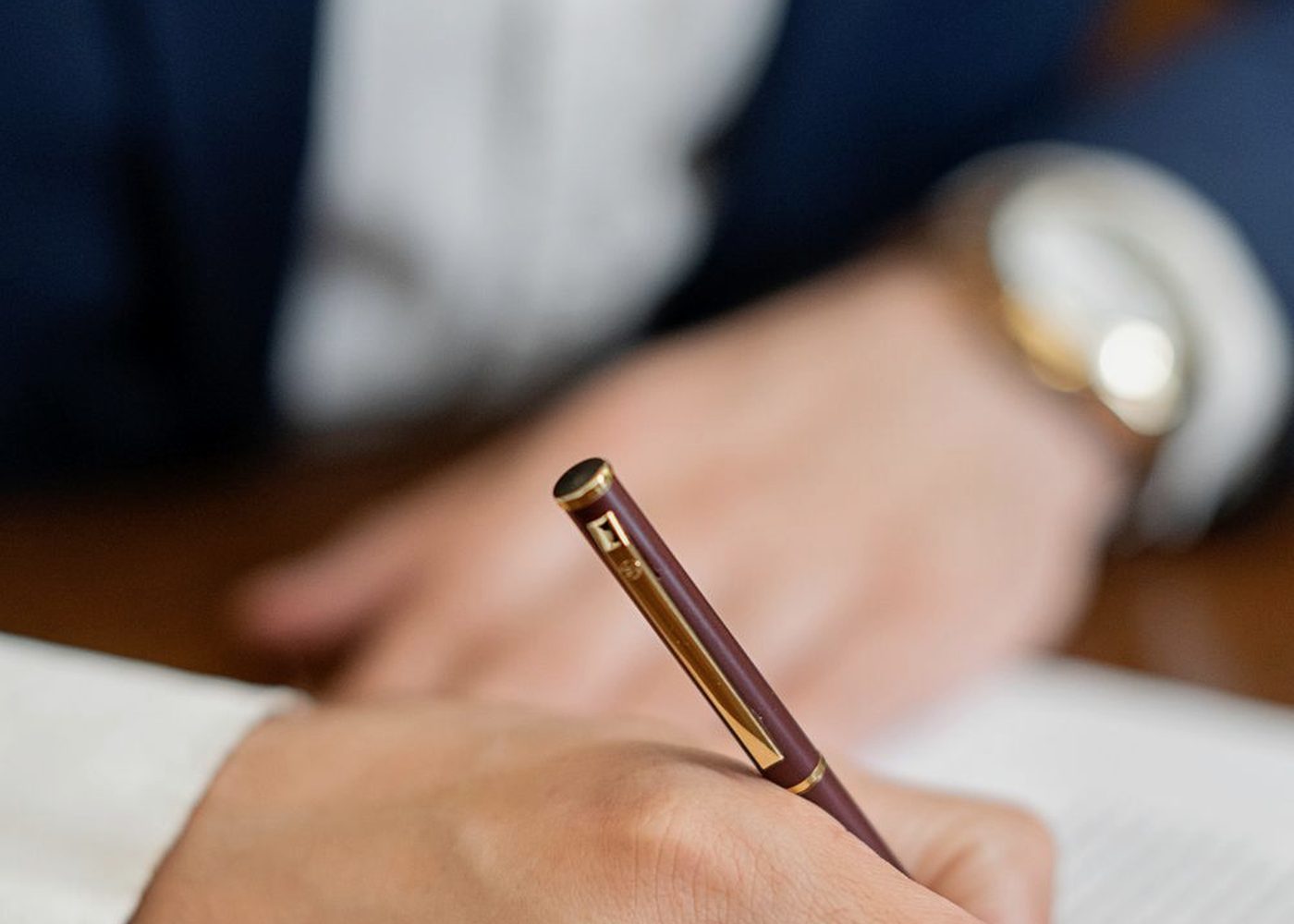A hand signing a document with a fountain pen