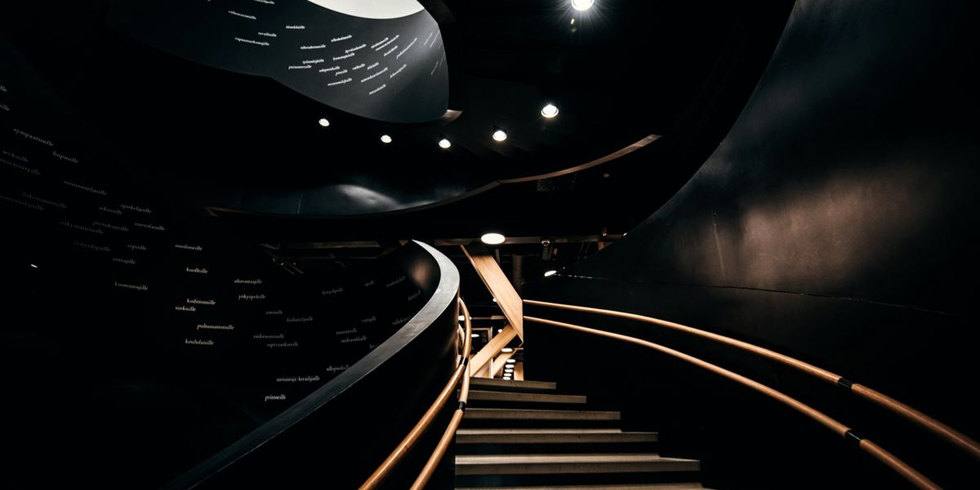 A curved staircase sweeping upward through a dark interior